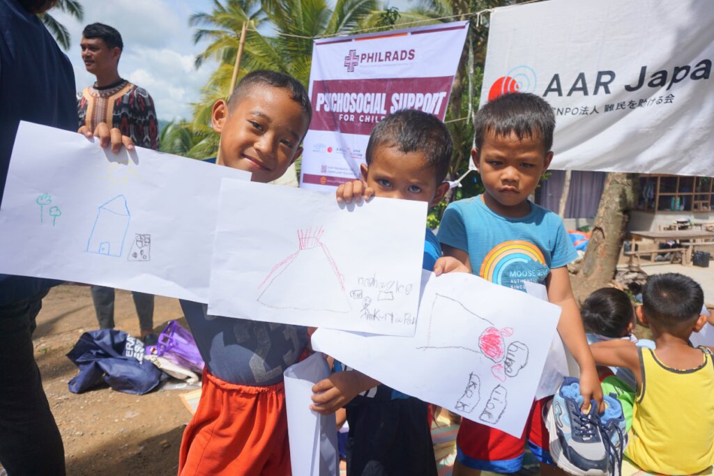 Children showing their drawings.
