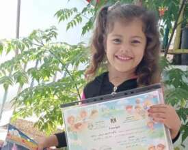 A kindergartener holding her certificate