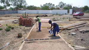Sithibisiwe preparing path for brick. Her project.