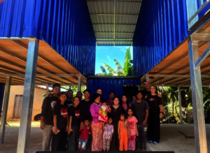 Mrs. T and her family in front of their new home