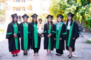 Six of eight gradutes in their graduation gowns.
