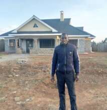 Enoch posing in front of a finished house