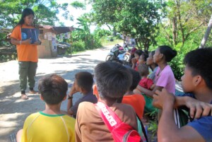 A volunteer reads out to children in Puerto Galera