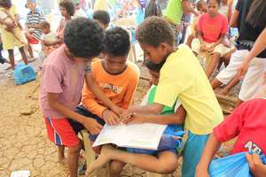 Aeta children working on the book activity pages.