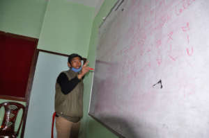 Harilal Limbu demonstrating how to write Limbu