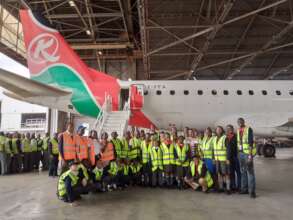 A group picture of students in front of a KQ plane