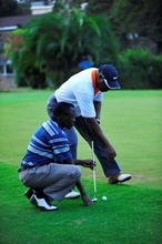 A blind golf player with his guide on the green.