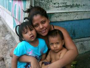 Carmela outside her home with her children
