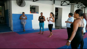 Standing by herself during yoga class (far left)