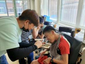 Minyeal helping to feed a young adult at Aemangwon