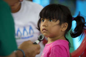 A little girl listens intently to Dr. Saul Camacho