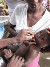 Mother holding baby while receiving medicine