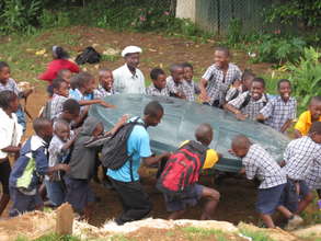 Children helping to bring tank lid to their school