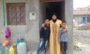 Mouna and her sons, in front of their house