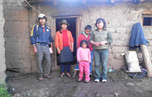 Nelly stands outside her home with her family.