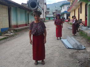 Ixil woman carries materials for her chicken coop