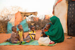 Nadifu sits besides her shelter with her children