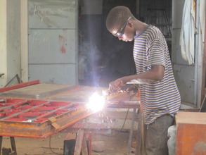 A boy builds new desks in his community