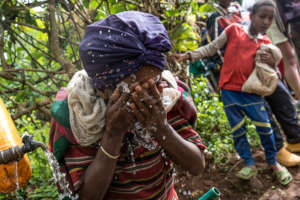 Woman washing her face at an Orbis supported pump