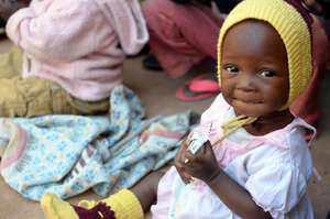 A young girl eats Plumpy'Nut at a health clinic