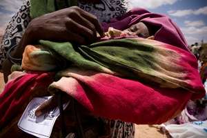 A mother holds her baby while awaiting UNHCR aid.