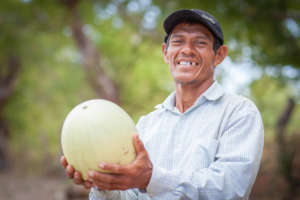 Justo holds up a watermelon he's grown in Luz
