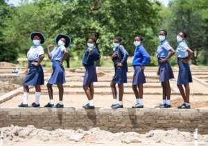 Girls stand along the foundation of the dormitory