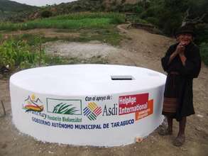 An older woman with her community's new water tank