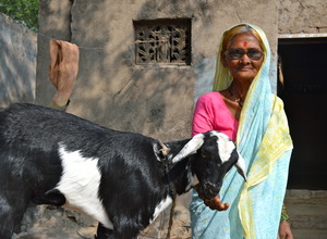 A village woman proudly stands with her goat