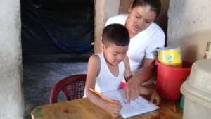 Child learning from home with the help of his mom.