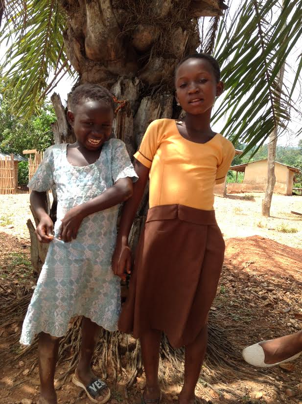 two young sisters stand next to each other smiling