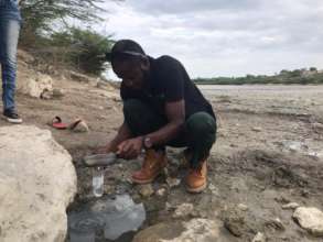 Taking a water sample from a drinking water puddle