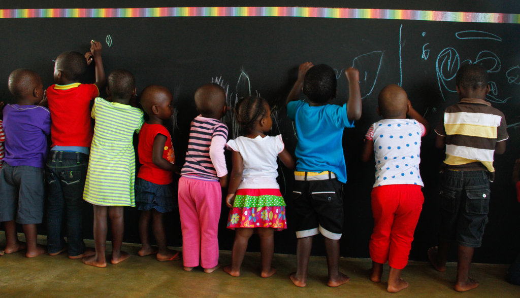Learners draw on chalkboard wall in new classroom