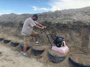 volunteer compacts earth into tire framework
